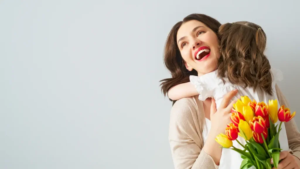 Festa della mamma: una donna che abbraccia un bambino con dei tulipani in mano