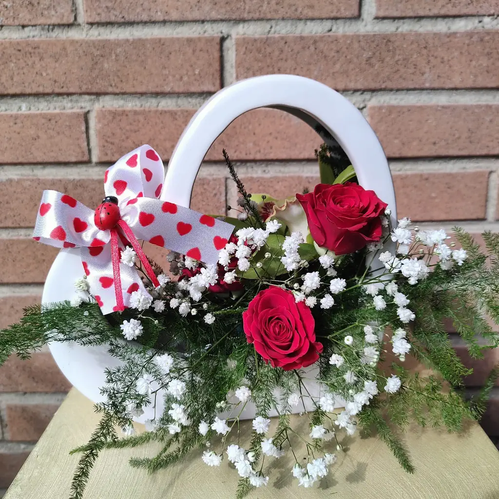 un cestino bianco a forma di cuore con rose rosse e fiori bianchi