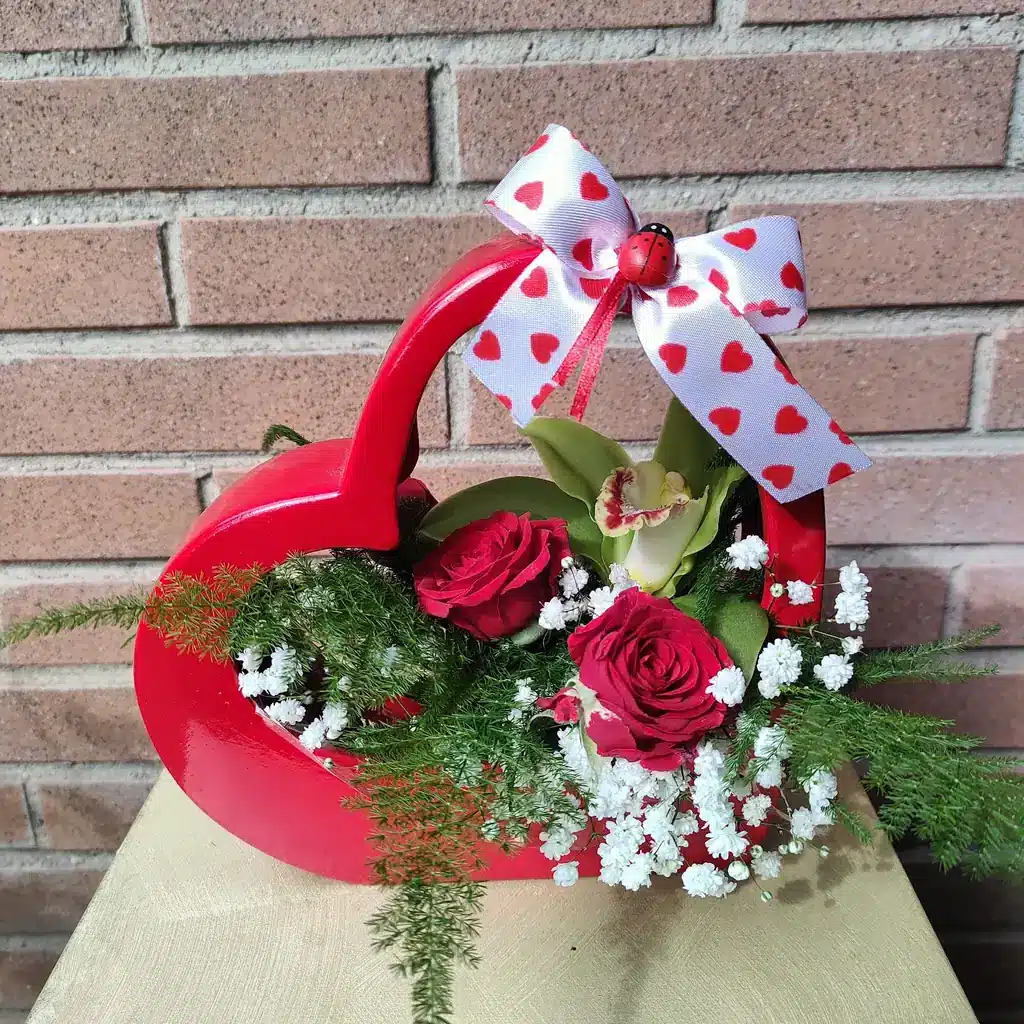 un cesto a forma di cuore rosso con fiori rossi e fiori bianchi