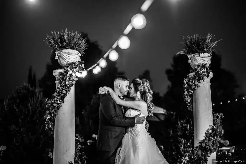 Matrimonio di gianmarco ed eleonora: di notte, gli sposi condividono una danza sotto una fila di luci, incorniciata da colonne decorate con motivi floreali.